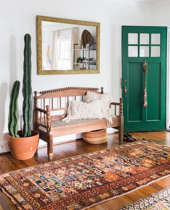 A boho rug, a vintage wooden bench, cacti and a mirror ina  gilded frame