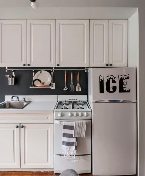 a traditional white kitchen with a chalkboard backsplash that features a holder for cook ware