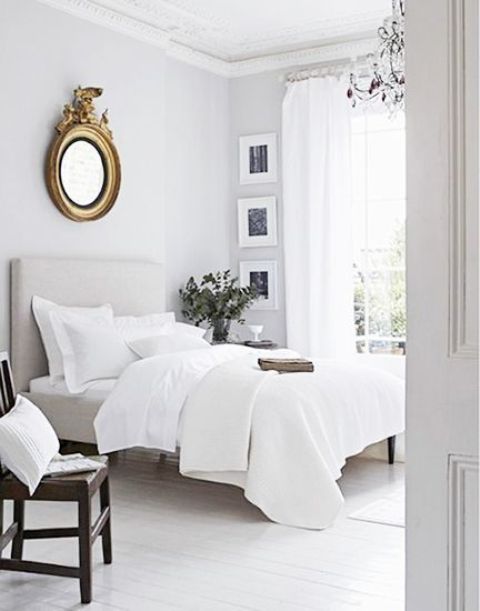 an airy and neutral space with sheer curtains, crispy white bedding and some darker touches for depth