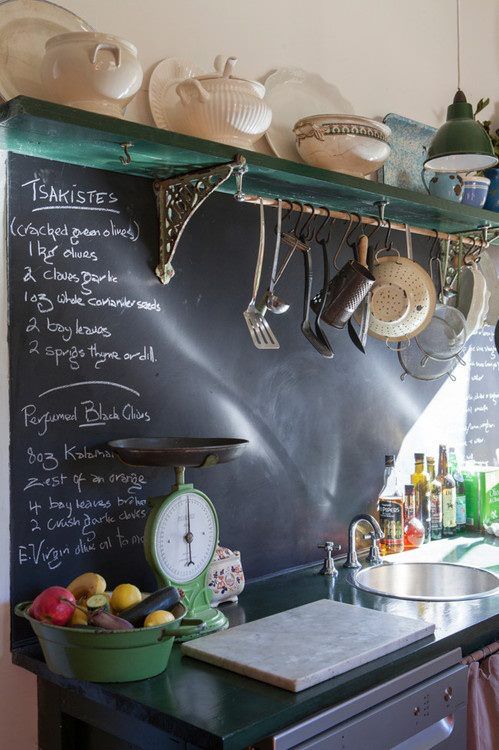 a vintage space with dark shabby shelves and countertops and a chalkboard backsplash