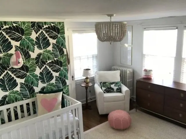 a cool nursery with a leaf print wall, pink touches and a flamingo head and a glam chandelier
