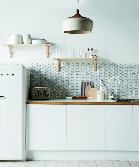 a minimalist white kitchen with wooden touches and a grey marble hexagon tile backsplash