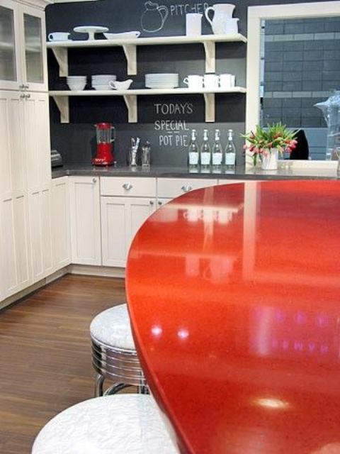 a white kitchen, a chalkboard backsplash and a red dining table for a bold look