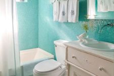 17 small turquoise bathroom tiles that cover the walls and the floor and contrast whites used in decor