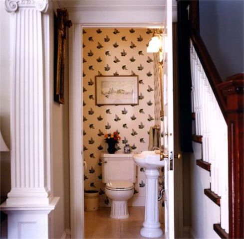 vintage printed wallpaper and aartworks make the powder room connected to the living room