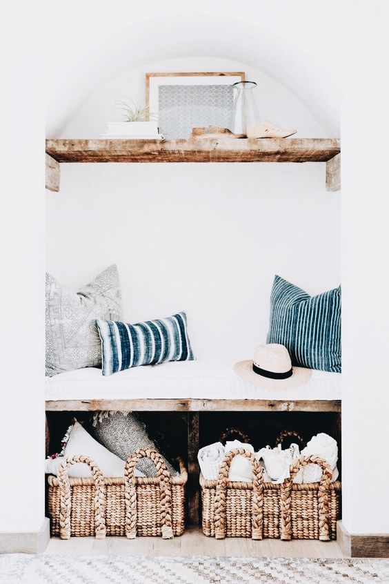 A built in bench with baskets for storage and a shelf with airplants over the bench for a small entryway