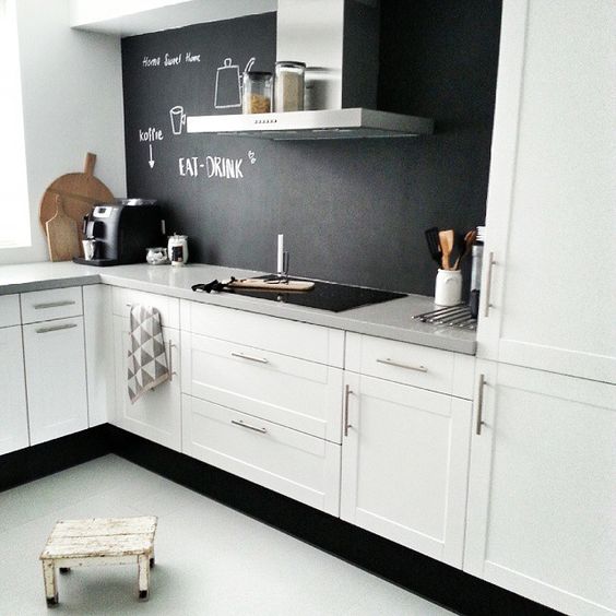 a white Scandinavian kitchen with a chalkboard backsplash that contrasts and adds depth to the space
