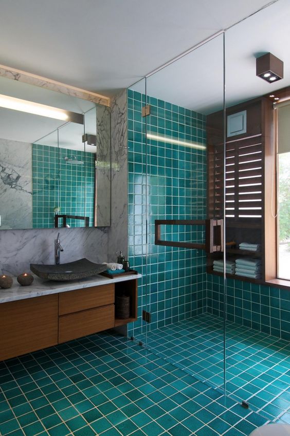 turquoise and teal tiles covering the floor and the shower contrast the rich shades of wood and create a mood