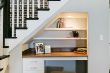 19 a little built-in home office nook with a built-in desk and shelves and lights and a small stool