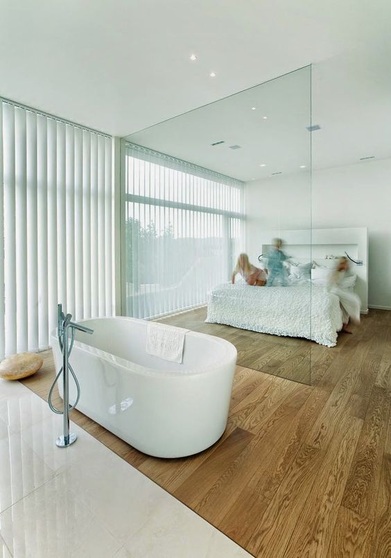 a minimalist bedroom and a bathtub separated with a glass divider so that both zones made a benefit from the views