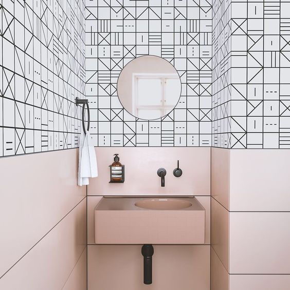 pink panels and a sink contrast the geometric black and white tiles and create a unique space