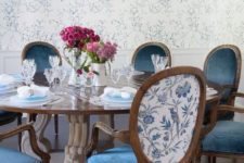 19 refined vintage chairs with blue velvet seats and floral printed fabric on the backs to match the wallpaper