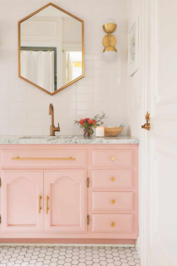 a light pink sink console with a marble top and gold handles and knobs are ideal for a glam bathroom look
