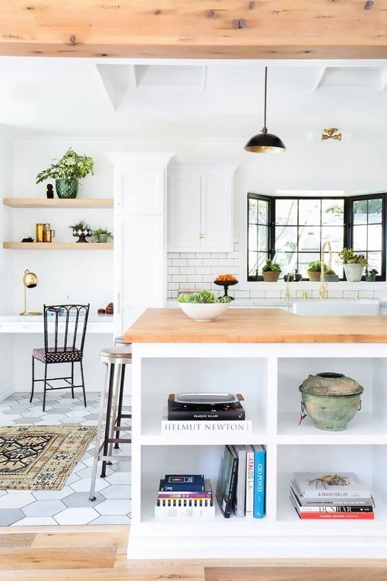 A modern farmhouse kitchen with a small home office nook by the window, with built in shelves and a desk