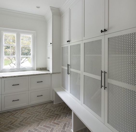 a white laundry room with all the stuff covered with wood lettice doors creates a perfect uncluttered look