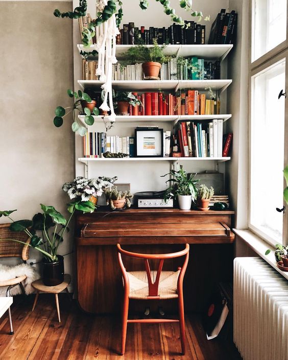 a boho home office nook with floating shelves by the window is incorporated in the living room
