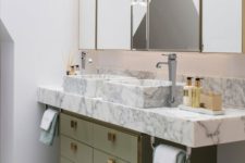 21 a muted green sink stand with gold knobs and a white marble vanity plus sinks create a luxurious combo
