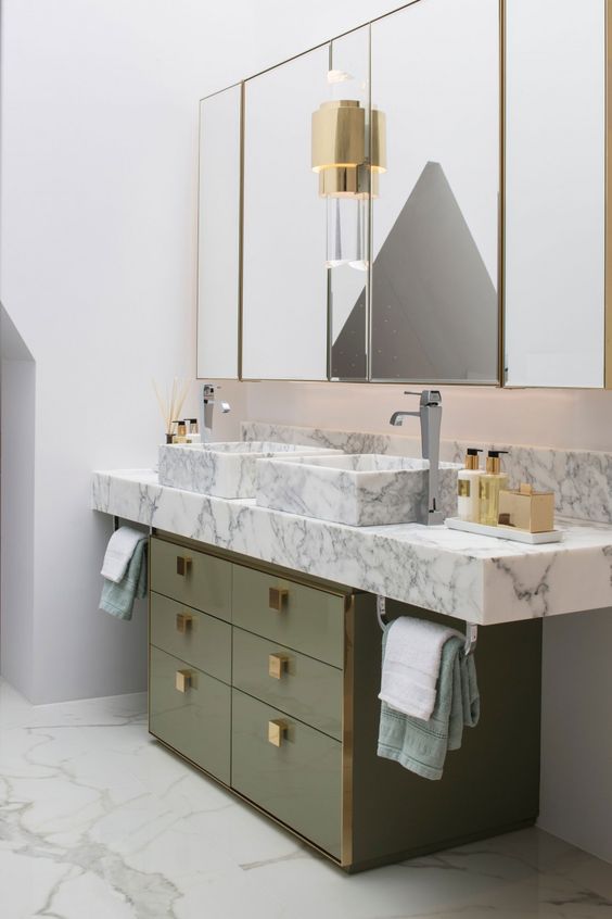 a muted green sink stand with gold knobs and a white marble vanity plus sinks create a luxurious combo