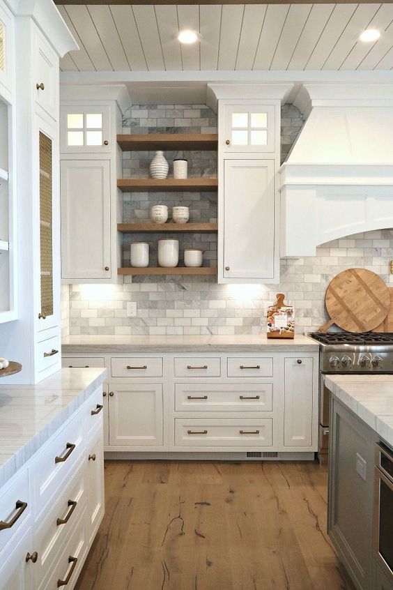 a traditional white kitchen with grey marble subway tiles on the backsplash and walls plus wooden touches