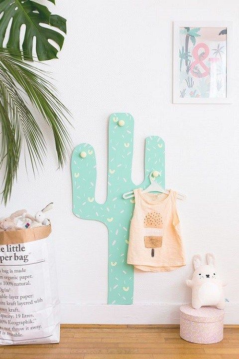 a colorful cactus decoration with hooks for hanging clothes an other stuff in a kid's room