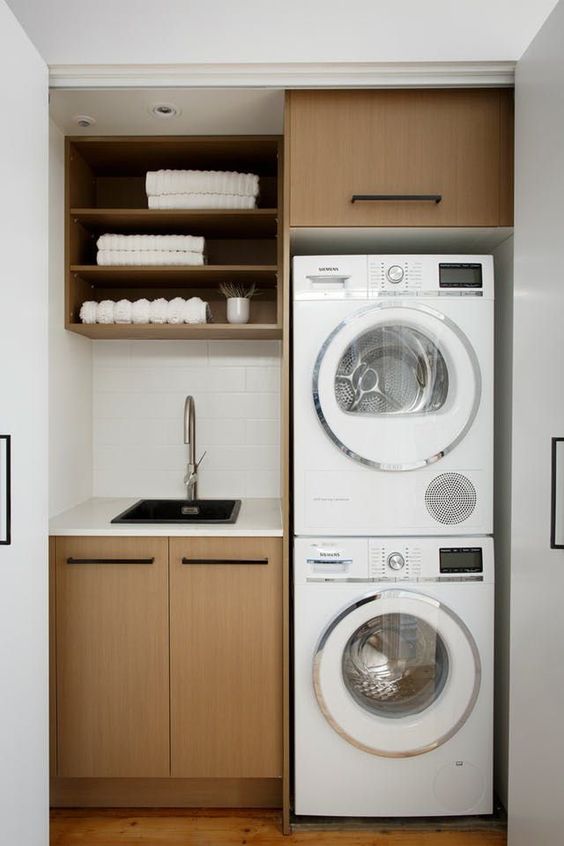 a comfy laundry under the stairs with a washing machine, a dryer, built-in cabinets and even a sink