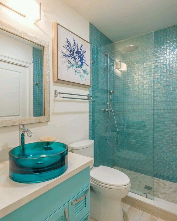 A glass turquoise round sink makes a colorful and stylish statement in the sea inspired space