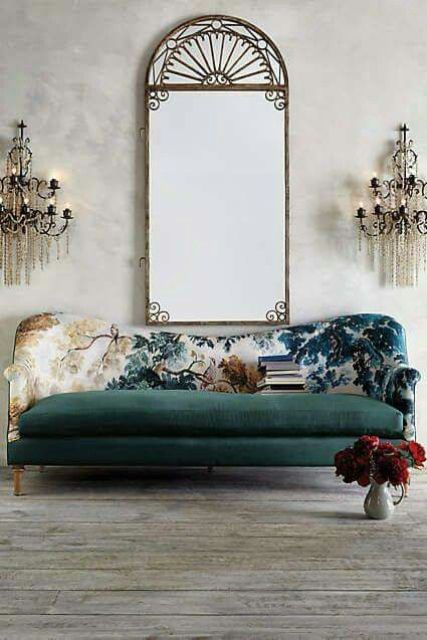 a gorgeous sofa with a dark green seat and base and a botanical print back