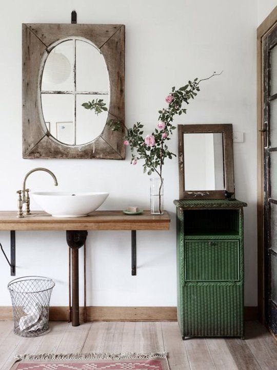 a green cabinet, a wood clad mirror, a wooden vanity and a a vintage faucet