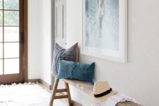 22 a reclaimed wood bench with trestle legs, chambray pillows, a sea-inspired artwork over the bench