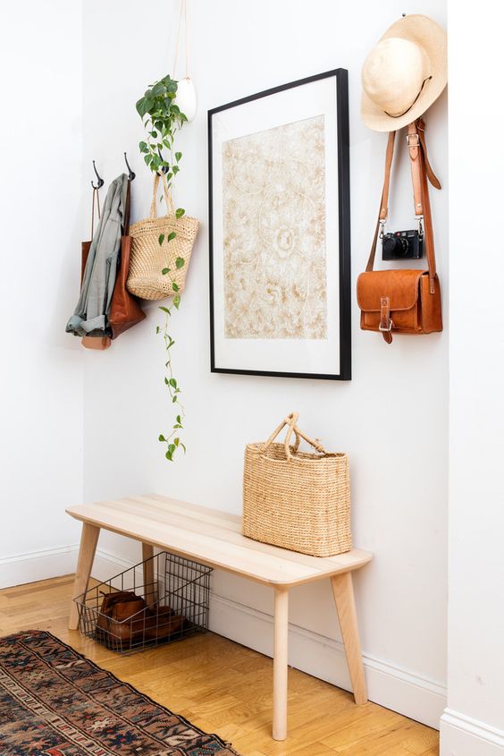 A simple wooden bench, a metal basket, an artwork, a cascading plant and a vintage camera