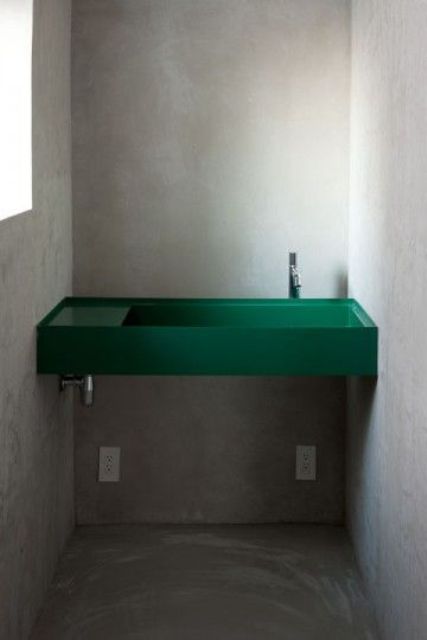 a small industrial powder room is spruced up with a minimalist emerald sink built-in between the walls