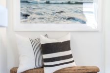 23 a simple beachy entryway with a wooden bench, a basket, a sea artwork and striped pillows