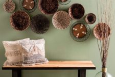 23 a wood and metal bench, woven and fringe pillows, an arrangement of plates and some branches