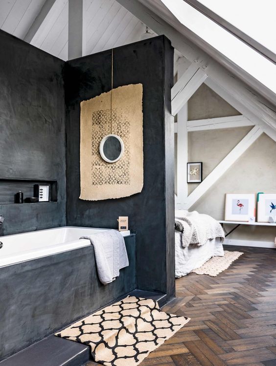 an attic bedroom with a bathtub zone separated with dark concrete from all the sides