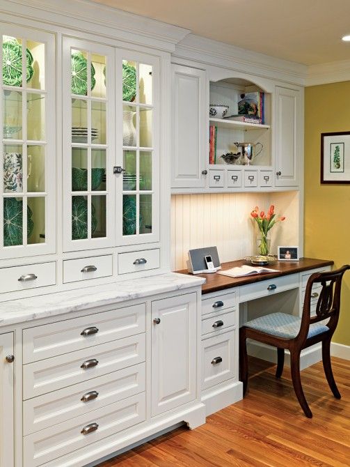 a traditional white kitchen with a marble countertop and a desk in the corner with a dark countertop