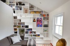 24 bookshelves built in into the wall and staircase for saving space in a small living room