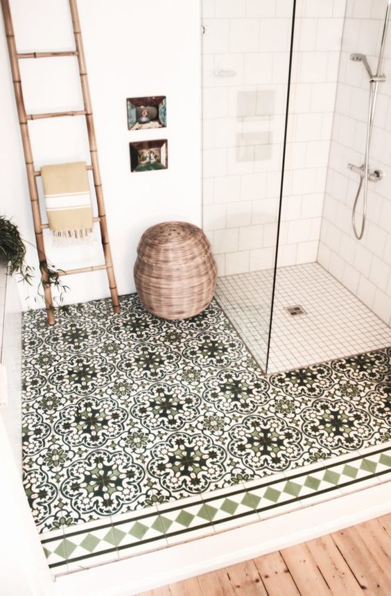 a wooden floor, a ladder as a towel rack, a basket for storage and mosaic tiles on the floor