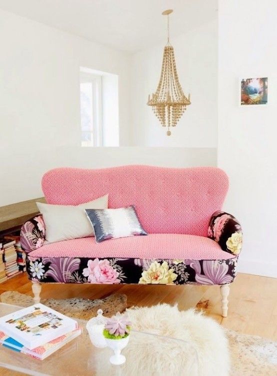A cute pink loveseat with bright floral base and armrests to make it less boring