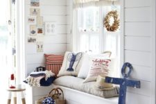 26 a whitewashed beach entryway with a windowsill bench, a stool, a shell wreath and some printed pillows