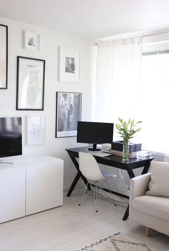 a Scandinavian living room with neutral furniture, a black desk by the window, a monochromatic gallery wall and a TV