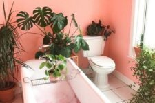 a coral pink bathroom with potted plants, a clawfoot tub and potted cacti is gorgeous and fun