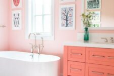 a light pink bathroom with a gallery wall, a coral vanity, a coral printed rug for a unique and very cute look