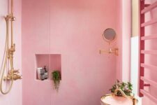a light pink bathroom with a shower space, a niche shelf, a black vanity with a bowl sink and gold fixtures