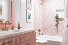 a lovely pink bathroom with printed tiles, pink and white penny tiles, a pink fluted vanity, brass fixtures and potted greenery