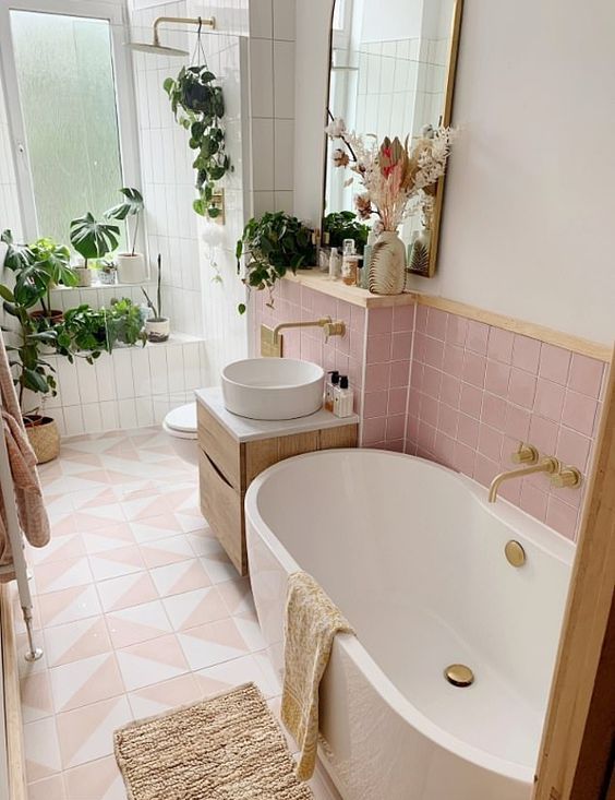 a modern bathroom clad with pink and pink geo tiles, a shower space with potted plants, a vanity with a sink and an oval tub