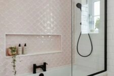 a modern bathroom in blush, white and black, with fishscale tiles, black fixtures and penny ones on the floor