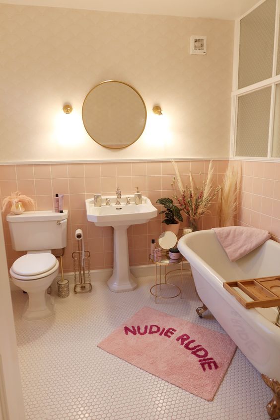 A neutral and blush bathroom with white vintage style appliances, pink textiles and some pampas grass
