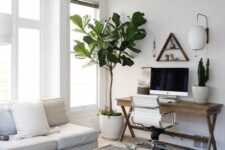 a neutral boho living room with a white corner sofa and neutral pillows, a coffee table, a trestle desk and a white chair, some potted plants