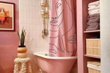 a pink and white bathroom with a pink free-standing tub, a printed curtain, geo tiles on the floor and some decor