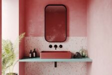 a pink bathroom with bright walls, terrazzo elements, a pink sink and black touches for some drama